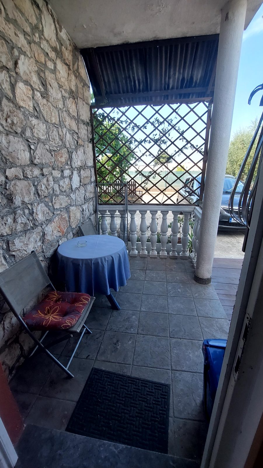 Natkrivena terasa sa stolom i stolicama uz kamenu kuću